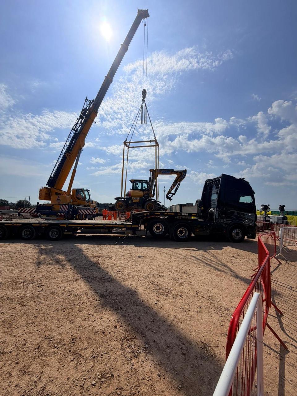 Crane lifting an excavator onto a Dunkirk low-loader trailer
